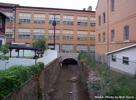 A stream flowing through a tunnel under a school